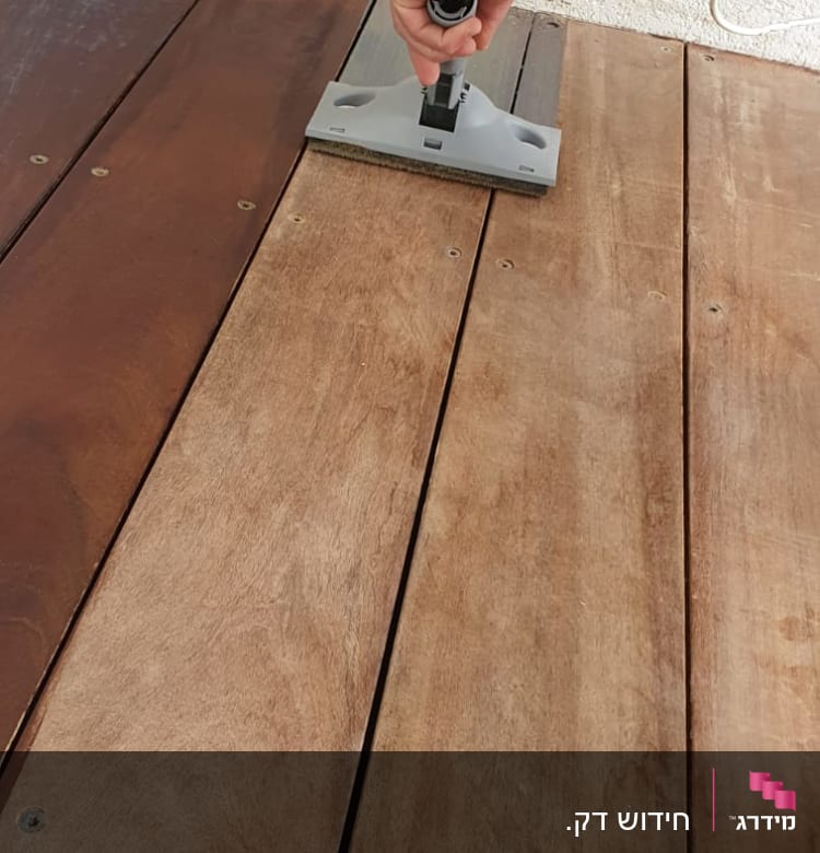 יד מחזיקה כלי לניקוי רצפת עץ בגינה